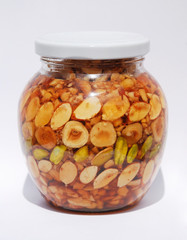 A jar of Greek honey and nuts (pistachios, peanuts, hazelnuts, pine nuts, almonds, walnuts) in natural light
