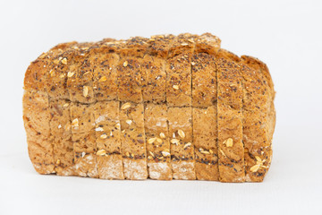 Sliced cereal bread with oatmeal and seeds. Traditional rye loaf cut for sandwiches isolated on white background. Studio shot. Side view. Homemade bakery and cooking at home concept