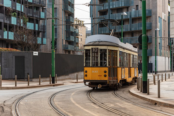 Naklejka na ściany i meble Yellow urban tram runs along the city tracks