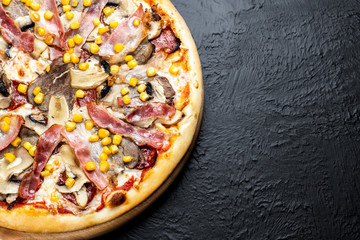 VIENNESE pizza on a black background, tomato-based with mozzarella, veal, chicken fillet, bacon, Napoli salami, corn and mushrooms
