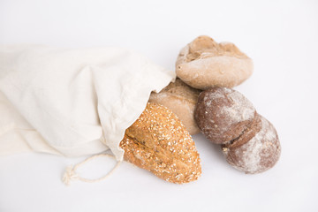 Loafs and buns of rye and wheat wholegrain bread in fabric bag. Closeup shot. Isolated object on white background. Food or bakery concept