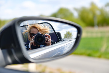 Frau fotografiert aus dem Auto heraus in den Rückspiegel
