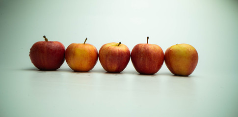 Five fresh red apples in line on a white background