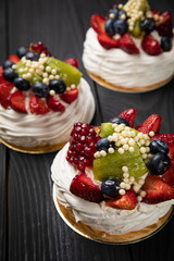 
French dessert Anna Pavlova on a black plate and a dark background