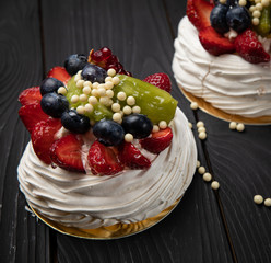 
French dessert Anna Pavlova on a black plate and a dark background
