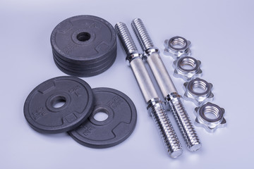 Obraz na płótnie Canvas two disassembled sports dumbbells for weightlifting and sports training on a gray background