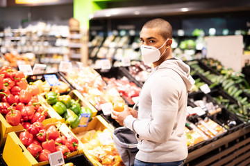 Einkaufen zur Zeit des Coronavirus, Mann mit Atemmaske in einem Supermarkt  