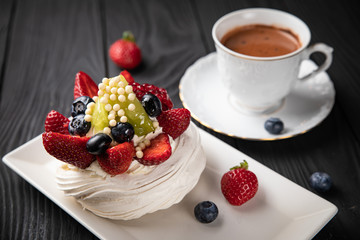 
French dessert Anna Pavlova on a black plate and a dark background