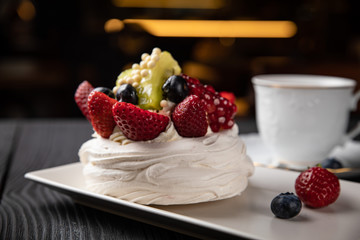 
French dessert Anna Pavlova on a black plate and a dark background