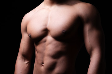 Muskulöser Männerkörper vor schwarzem Hintergrund 