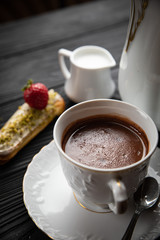 Hot chocolate in a white dish with cakes on a dark background 