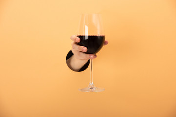 Fototapeta na wymiar cropped view of woman holding glass of red wine on orange
