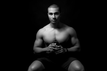 Fototapeta na wymiar Muskulöser Mann mit Trinkflasche vor schwarzem Hintergrund 