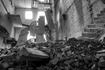 Destroyed concrete building inside with a pile of construction debris in the foreground. Background.