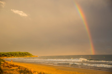 Sunset and rainbow in Platja Llarga beach, Tarragona, Spain