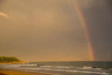 Sunset and rainbow in Platja Llarga beach, Tarragona, Spain