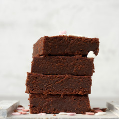 stack of square baked brownie chocolate cake slices on a white background