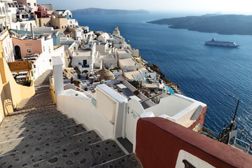 Stairs in a typical Greek village with church tower lying far over the ocean, Fira, Santorini, Greece