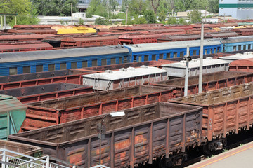 Old and rusty railway cars and trains are standing at the station. Commodity and passenger cars.