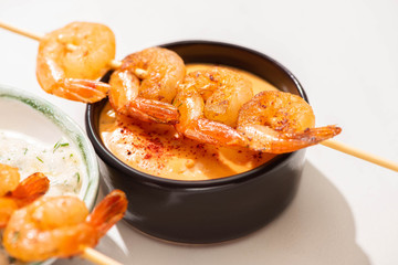 close up view of delicious fried prawns on skewers with sauces on white background