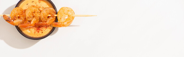 top view of delicious fried prawns on skewer with sauce on white background, panoramic shot