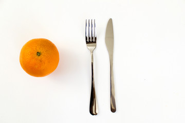 Orange fruit  with fork and knife on white table top view diet fitness healthy sports food vegan meal concept 
