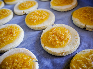 round gluten-free cookies made from rice flour and cottage cheese with orange jam and crushed almonds on parchment paper. gluten-free diet. homemade baking cookies