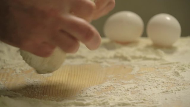 Male hands knead fresh homemade dough on a special kitchen board in the home kitchen, close up shot. Home baking pastries. Baker kneading dough in flour on table. Baker Kneads Dough And Making Bread.