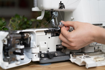 repair of sewing equipment, overlock. hand and a screwdriver fixes the breakage sewing machine