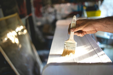 Male Hand Carpenter painting wooden furniture