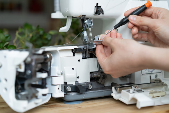 repair of sewing equipment, overlock. hand and a screwdriver fixes the breakage sewing machine