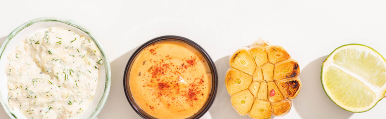 top view of garlic, lime and sauces on white background, panoramic shot