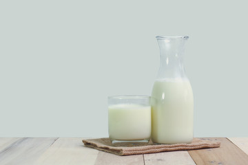 A bottle of rustic milk and glass of milk on a wooden table