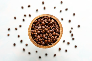 Ganze geröstete Kaffeebohnen in einer Holzschüssel auf einem weißen Hintergrund. Draufsicht und Nahaufnahme.