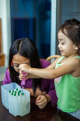 Child injecting organic fertilizer into small containers to be placed into the plant soil. Fine motor skills activities for kids.