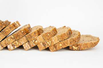 Cropped view of fresh loaf with poppyseeds cutting on slices. Sliced bread with cereals made of rye flour isolated on white background. Studio shot. Side view. Homemade food and nutrition concept