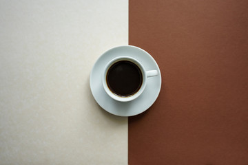 Draufsicht auf ein weiße Tasse Kaffee mit Untertasse auf einem weiß und braunen Hintergrund. Gegensätze, modern.