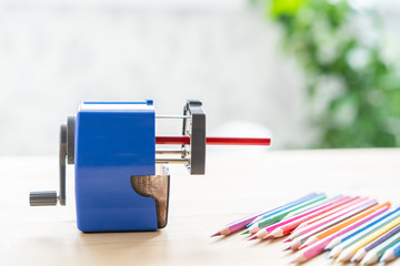 blue mechanical pencil sharpener with a handle for sharpening pencils at the table, school concept, place for text