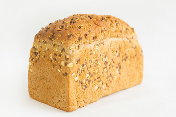 Fresh brick form bread baking at home. Crunchy whole loaf with cereals, oats, seeds isolated on white background. Studio shot. Selective focus. Side view. Homemade food and nutrition concept