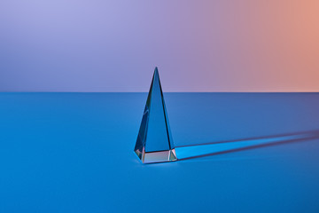 crystal transparent pyramid with light reflection on blue background