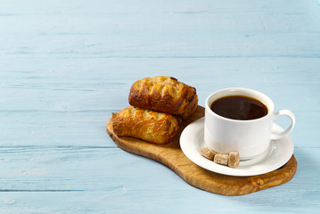 cup of coffee and bakery on light blue old wooden table