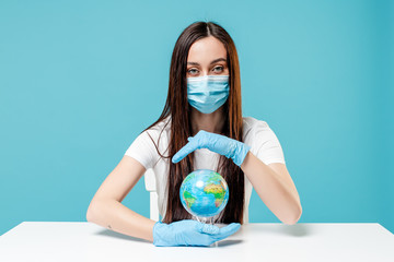 woman holding roof with hands under planet earth globe wearing mask on blue background. safety concept