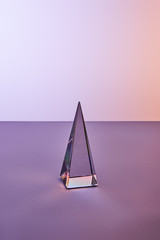 crystal transparent pyramid with light reflection on violet and purple background