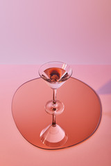 cocktail glass with liquid on mirror with reflection