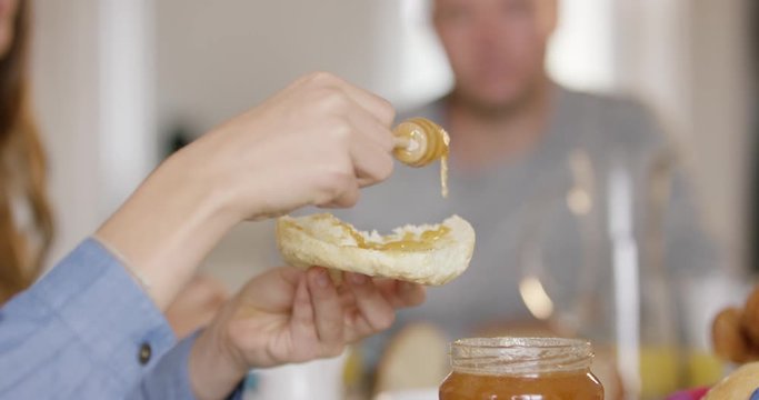 4K Close Up Of Girl Spreading Honey On A Slice Of Bread At Family Breakfast