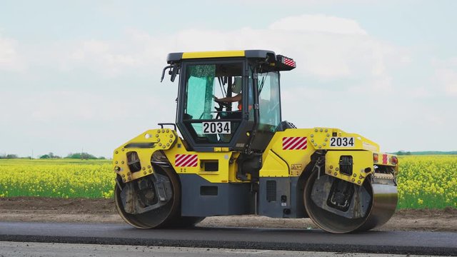 Roller machines make new asphalt roads. The asphalt paver squeezes hot asphalt.