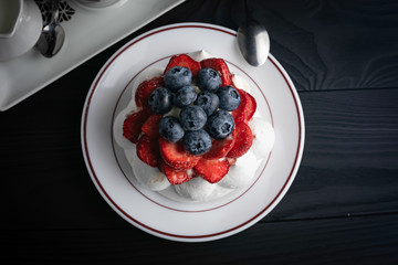 
French dessert Anna Pavlova on a black plate and a dark background