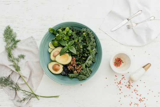 Table setting with a green plate with a vegan salad with kale and avocado