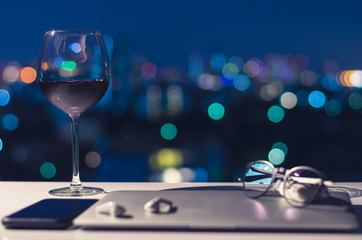 A glass of red wine put on table to enjoy the night after turning off laptop, smartphone and earphone for digital detox, social disconnect, gadget addiction concept.