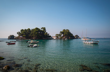 in the bay of Parga, an island and a chapel, boats are waiting on the blue Mediterranean sea,